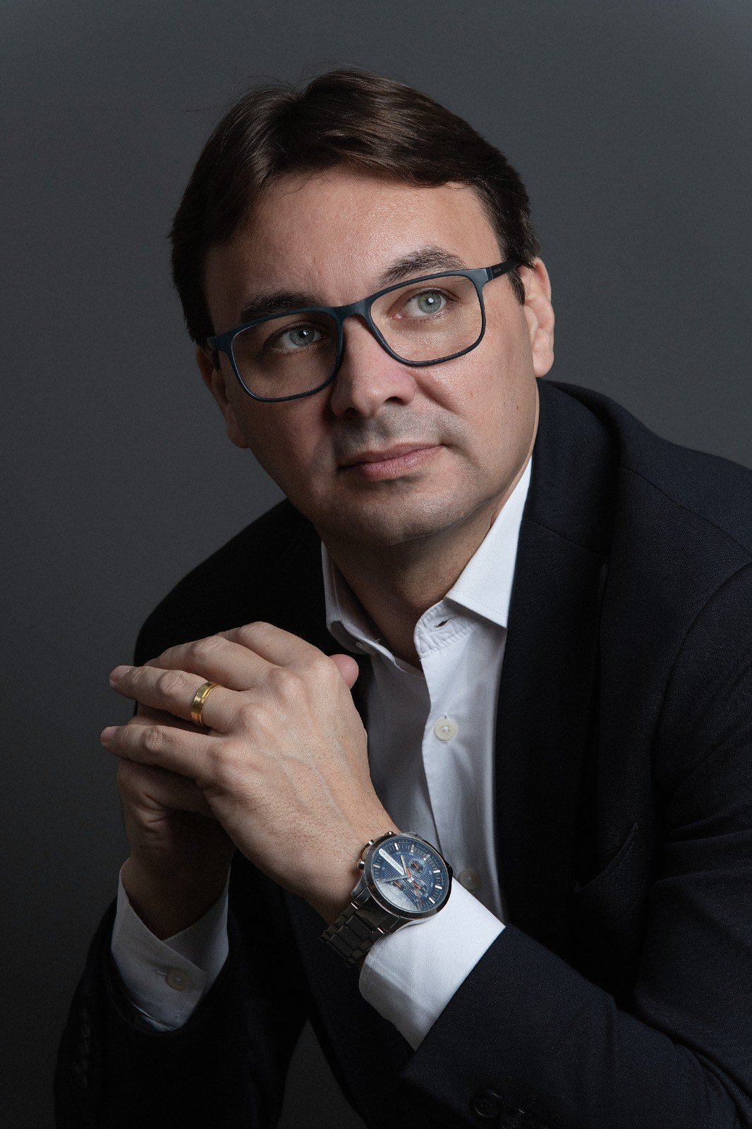 Marcel Lodetti Fábris em retrato de perfil, olhando para o alto, com camisa branca e blazer escuro